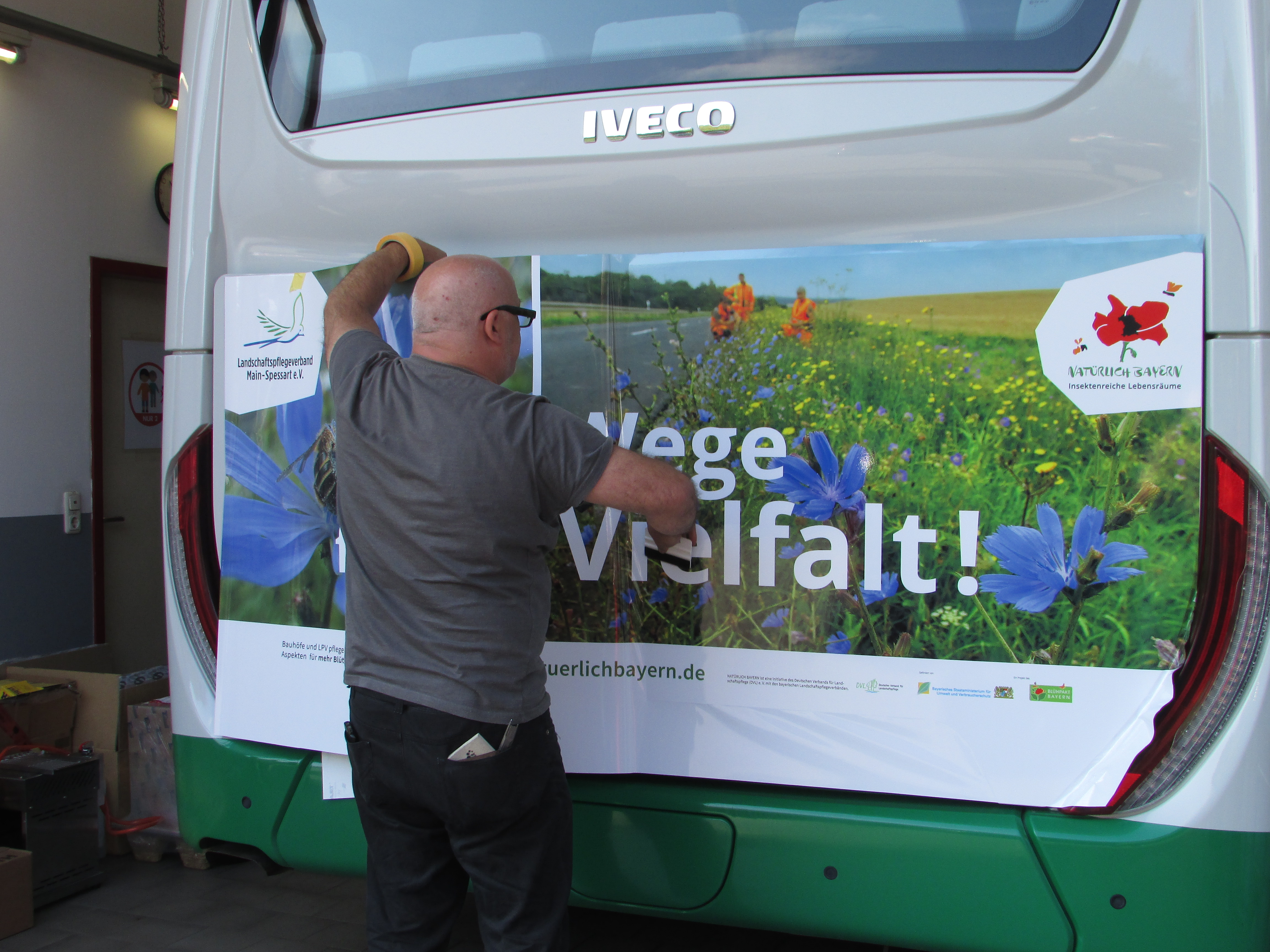 ein Mann installiert Werbetafeln auf einem Bus